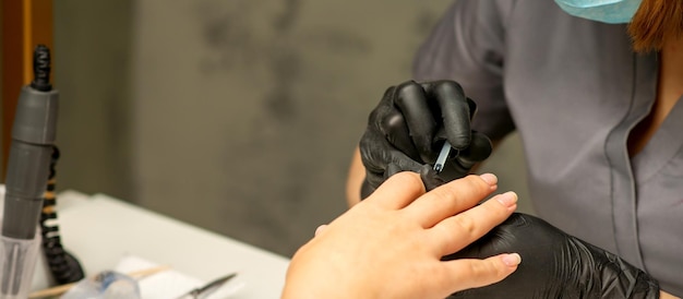 Manicure painting process Manicure master paint the nails with transparent varnish in a nail salon close up