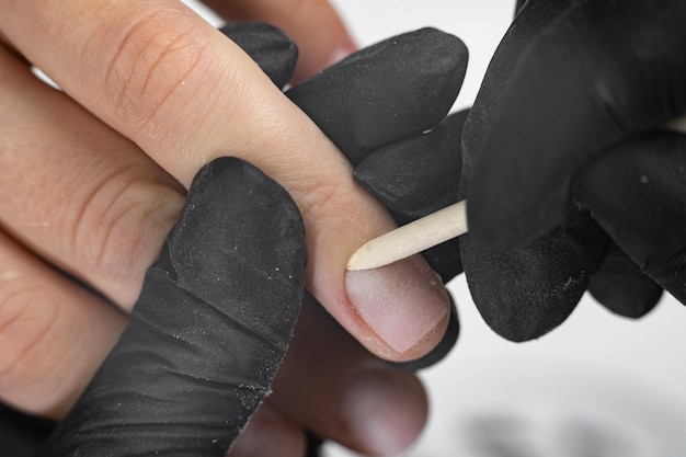 Photo manicure process the master forms the shape of the cuticles using a bamboo stick