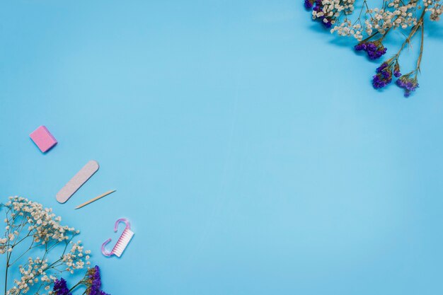 Manicure tools on a blue background are decorated with white gypsophila flowers