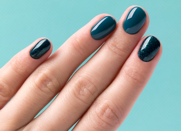 Manicured woman's hand on turquoise pastel table