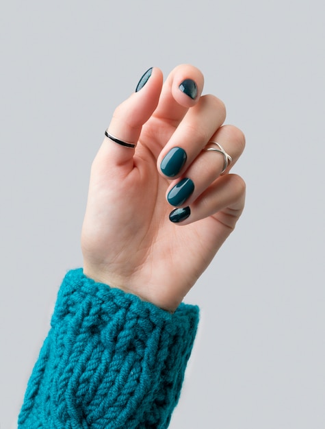 Manicured woman's hand in warm wool turquoise sweate