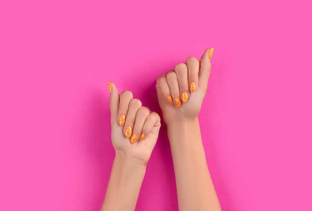 Manicured womans hands with trendy nail design on pink background