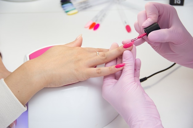 Manicurist apply nail Polish. Close-up of a woman applying nail Polish to her finger nails.Pink nails.