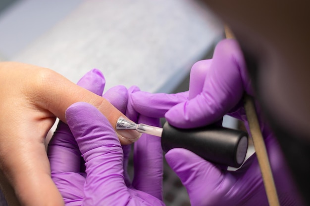 The manicurist makes nude gel polish nails for the client. The process of creating a manicure