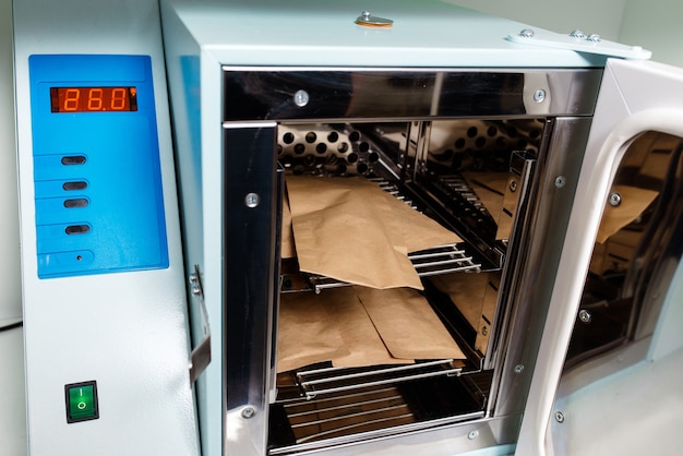 Manicurist sterilize her tools in the autoclave or oven. Master int he salon preparing her instruments for disinfection.