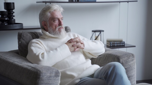 A manly confident old man is sitting on a chair A man sits with a thoughtful look