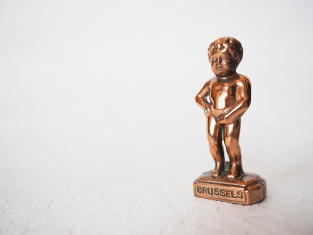 Manneken Pis statue on white background Brussels symbol Miniature bronze figurine of a naked boy urinating into a pool Metal souvenir Baby pissing