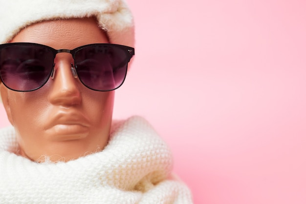 Mannequin with glasses and a scarf, discounts on winter clothes and accessories, on a pink background