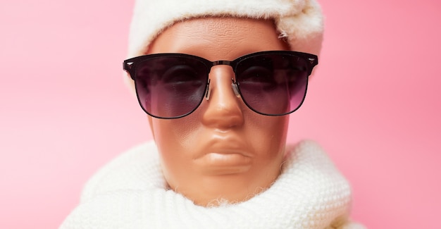 Mannequin with glasses and a scarf, discounts on winter clothes and accessories, on pink background