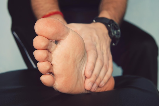 Mans hand being massaged a foot man with painful and inflamed gout on his foot around the big toe ar