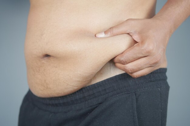 Photo mans hand holding excessive belly fat overweight concept