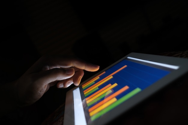 Mans hand working on digital tablet at office desk using self created chart