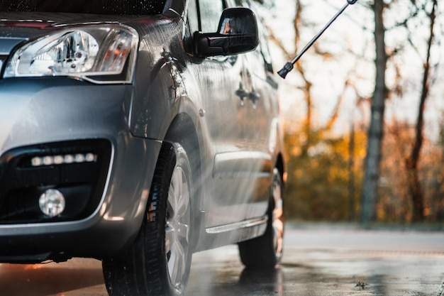 Manual car wash with white soap foam on the body Washing Car Using High Pressure Water