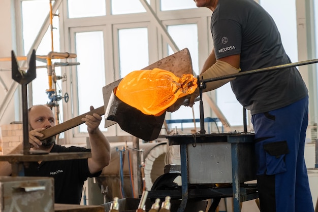 Manual glass production by glassblowing by worker at the factory