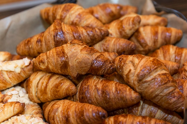 Many appetizing croissants in a basket on the buffet table Closeup Breakfasts and coffee breaks