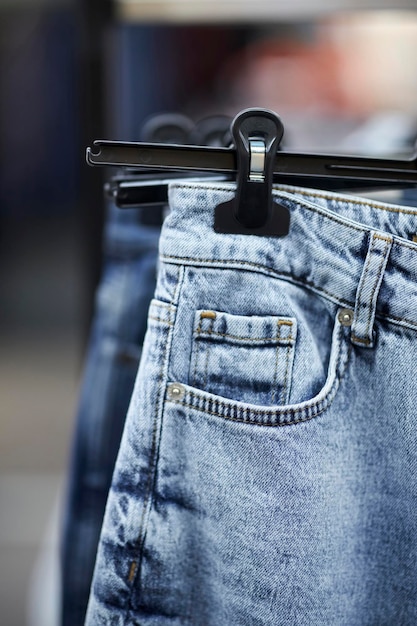 Many blue jeans hang on a rack in the clothing store. Jeans or denim pants hanging on a hanger.