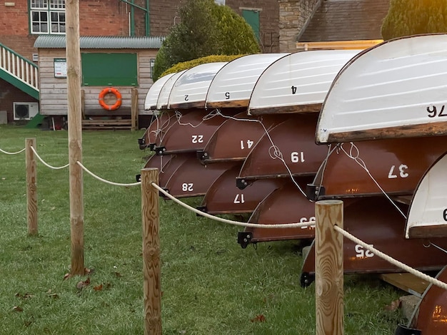 Many boats stored one on another on the grass at boat club