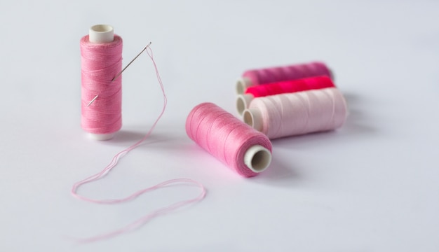 Many bobbins of bright sewing thread with a needle 