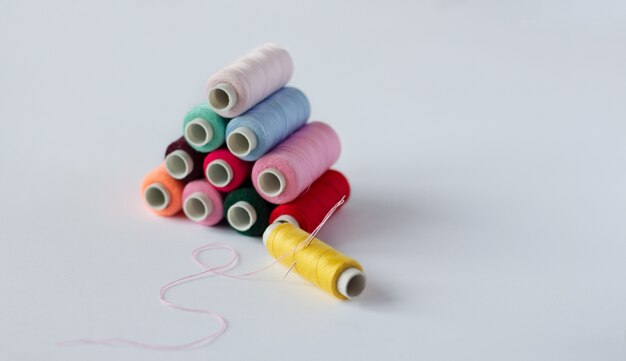 Many bobbins of bright sewing thread with a needle