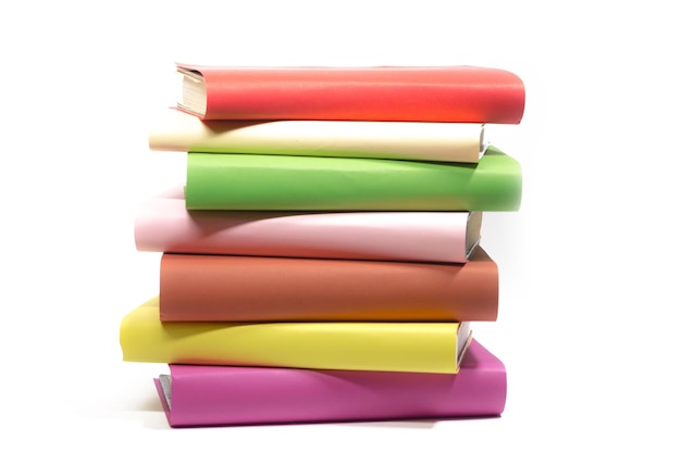 Many books of different colors lie in a stack unevenly on a white background insulator