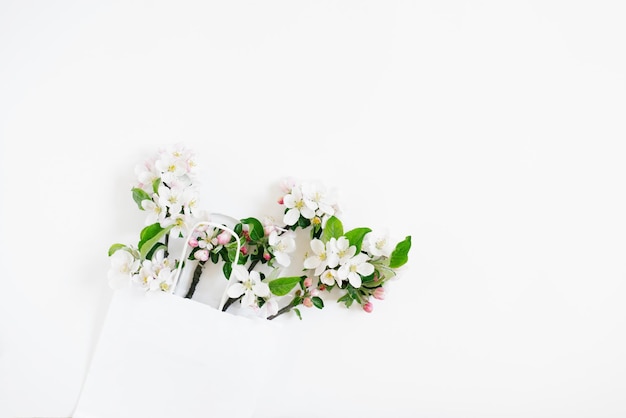 Many branches of an apple tree with flowers are in a paper shopping bag