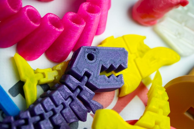 Many bright multicolored objects printed on 3d printer lie on flat surface