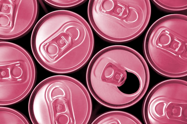 Many cans of soda soft drink or energy drink containers A lot of recycled cans made from aluminum Image toned in Viva Magenta color of the 2023 year