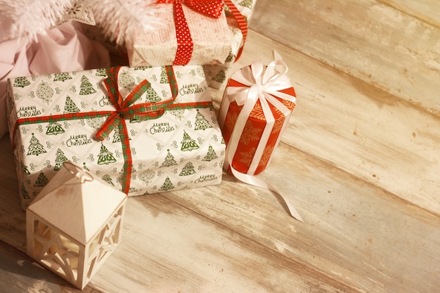 Many Christmas gifts and white lanterns under a Christmas tree with defocused lights