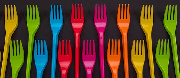 Many color plastic forks on a bright background