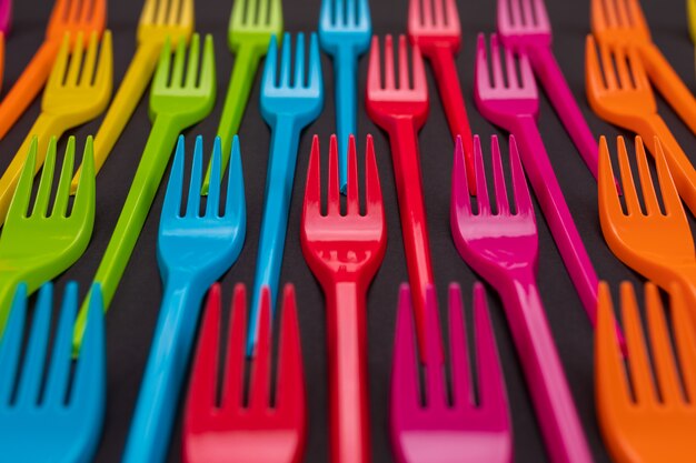 Many color plastic forks on a bright 