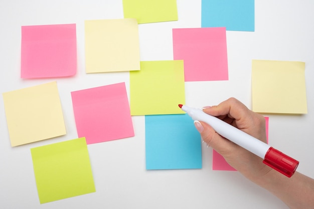 Many colored empty sticker notes on white wall Business people meeting and use notes to share idea on sticky note hand with red marker ready to write