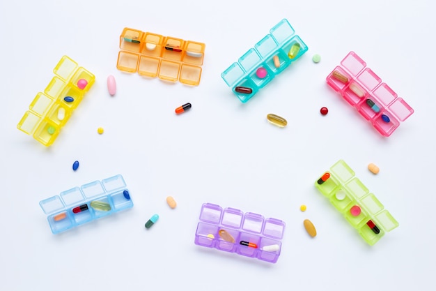 Many colored tablets and capsules with pill box isolated on white