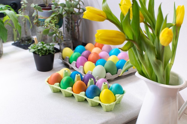 Many colorful easter eggs in carton box on table in kitchen interior