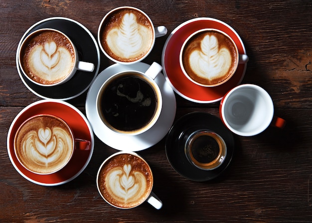 Many cups of coffee on wooden table, top view