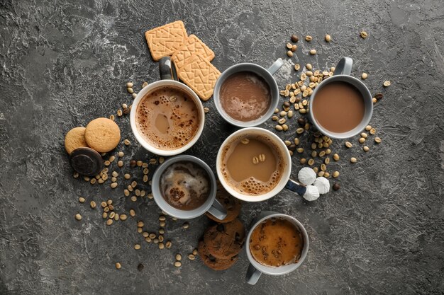 Many cups with tasty aromatic coffee and cookies on grey table, flat lay