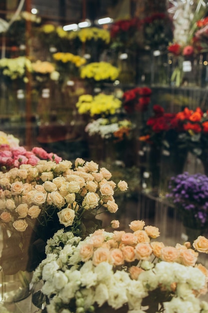 Many different flowers can be seen behind the glass window of the flower shop