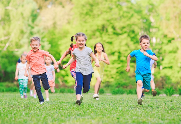 Many different kids, boys and girls running in the park on sunny summer day in casual clothes