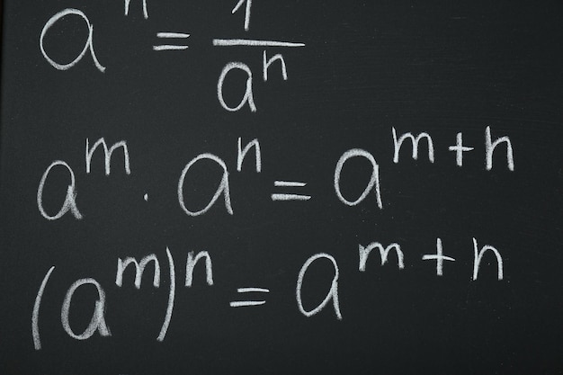 Many different math formulas written on chalkboard closeup