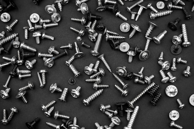 Many different screws scattered on a black background