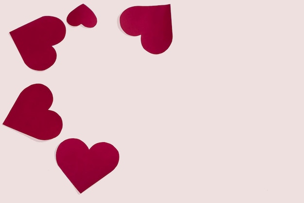 Many different shaped red paper hearts side by side on one side on a white background isolate