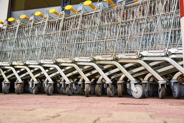 Many empty shopping carts on the shop parking. Row of shopping trolleys for supermarket buyers