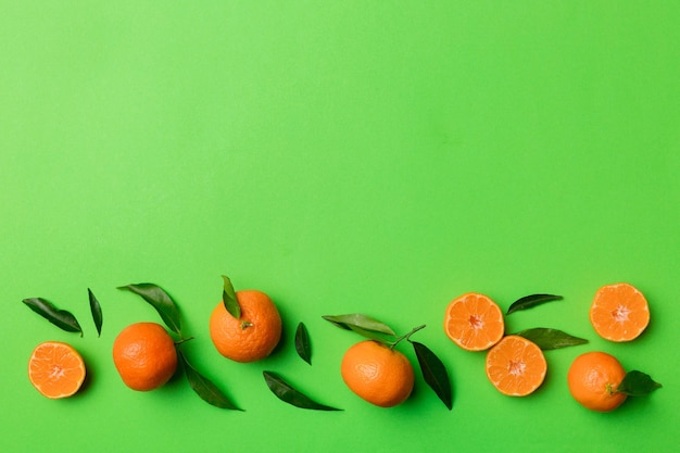 Many fresh ripe mandarin with green leaves on colored background top view space for text