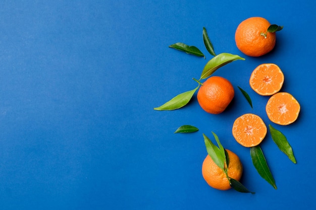 Many fresh ripe mandarin with green leaves on colored background top view space for text