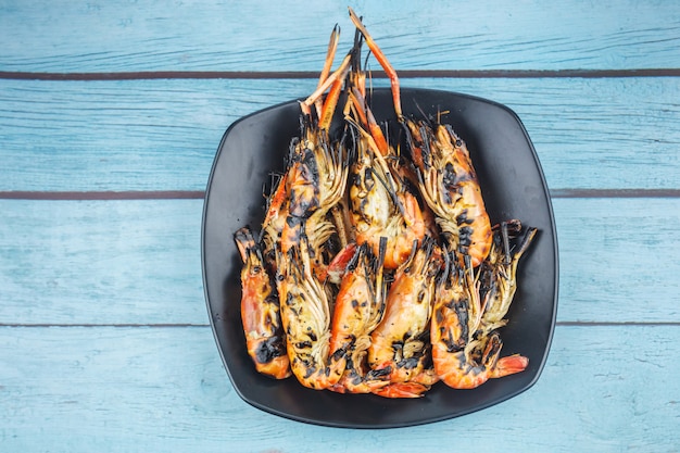 Many fresh river prawns grilled with seafood sauce Placed on blue wood background