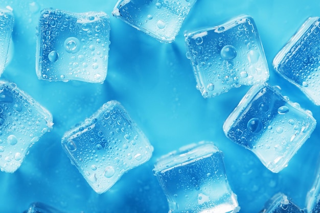 Many frosty and refreshing ice cubes with drops on a blue background Refreshing drinks in hot weather