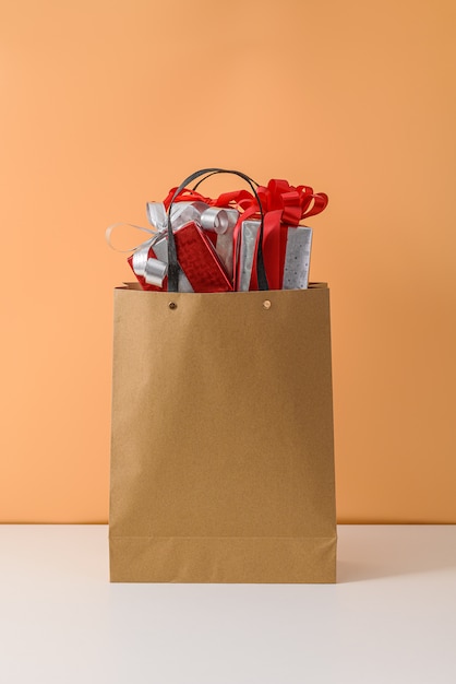 Many Gift Box with Red ribbon bow in Brown paper shopping bag. concepts New Year's gift or Christmas