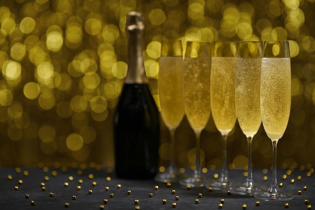 Many glasses of champagne in a line, selective focus. Golden background. Sparkling New Year background. Champagne bottle with toast of  glasses flutes.