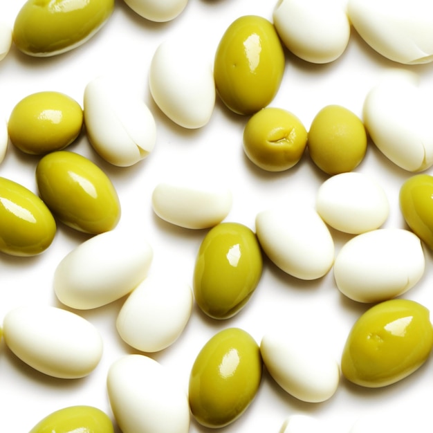 Many green olives are scattered on a white surface