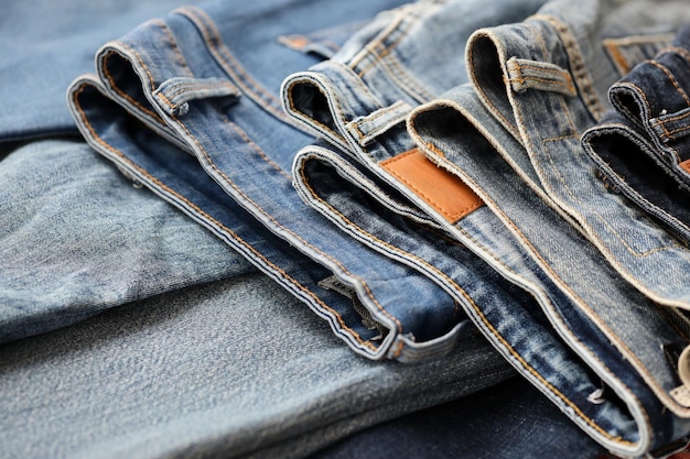 Many jeans in stack in wardrobe room Row of pants denim jeans in closet Concept of buy sell shopping and fashionable clothes