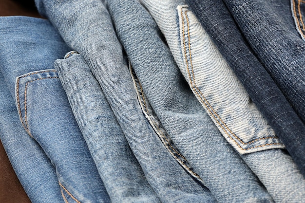 Many jeans in stack in wardrobe room Row of pants denim jeans in closet Concept of buy sell shopping and fashionable clothes